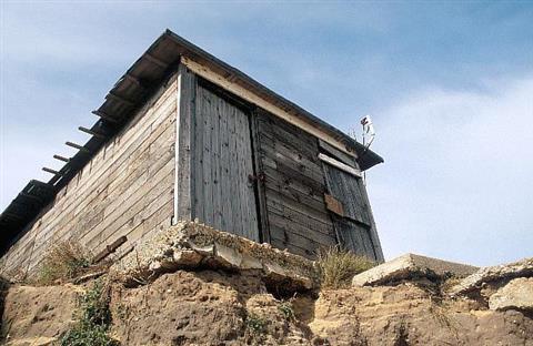 Hut perched over an eroded bank of sand