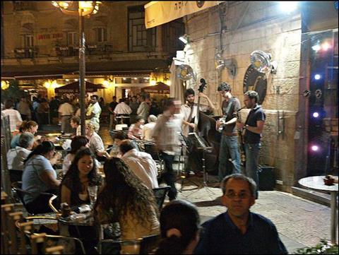Evening in a street cafe, with a band playing, on the corner of a busy street