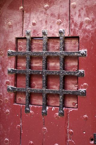 Ancient red prison door with iron grill