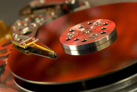 Internal view od the mechanism of a computer hard drive, bathed in a reddish light