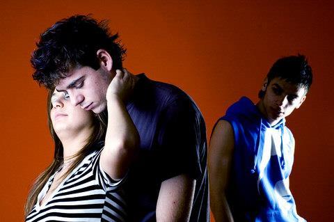 Two young people embrace affectionately whilst another looks on eviously